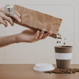 hand pouring coffee beans from paper bag into coffee cup
